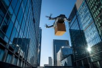 Drone delivering package between highrise buildings, London, UK — Stock Photo