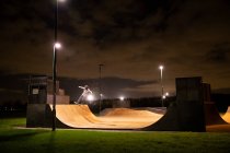 Junger Mann skateboardet nachts auf Skatepark-Rampe — Stockfoto