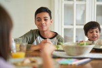 Портрет щасливого хлопчика, який обідає з сім'єю за столом — стокове фото