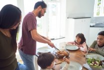 Familien servieren und essen am Esstisch — Stockfoto