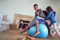 Família feliz jogando na bola de fitness na sala de estar — Fotografia de Stock