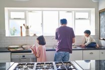 Familia haciendo platos en el fregadero de cocina - foto de stock