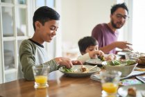 Happy family eating lunch at table — Stock Photo