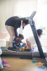Enfants avec des jouets distrayant mère sur tapis roulant — Photo de stock