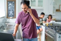 Mann arbeitet mit Kindern am Laptop in Küche — Stockfoto