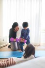 Mutter und Kinder üben mit Kurzhanteln im Wohnzimmer — Stockfoto