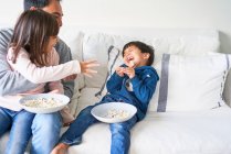 Playful family with popcorn on living room sofa — Stock Photo