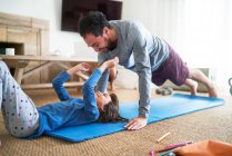Padre e hija juguetones haciendo ejercicio en la sala de estar - foto de stock