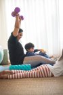 Mãe se exercitando com halteres na sala de estar com crianças — Fotografia de Stock