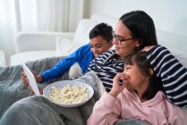 Мати і діти з попкорном дивитися фільм на цифровому планшеті — стокове фото