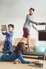 Padre haciendo ejercicio en la cinta de correr en la sala de estar con los niños - foto de stock