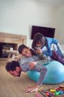 Playful kids on top of father exercising on fitness ball — Stock Photo