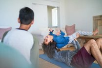 Padre juguetón levantando hija y haciendo ejercicio en la sala de estar - foto de stock