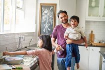 Portrait happy father and kids doing dishes in kitchen — Stock Photo