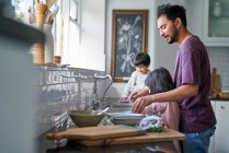 Father and kids doing dishes at kitchen sink — Stock Photo