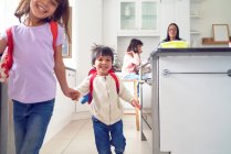 Happy brother and sister holding hands and leaving for school — Stock Photo