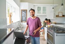 Portrait happy father working at laptop in kitchen with kids eating — Stock Photo