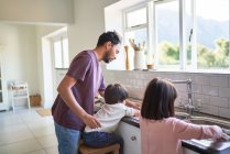 Padre e figli che lavano i piatti al lavello della cucina — Foto stock