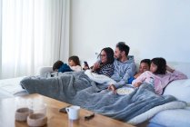 Сім'я розслабляє і дивиться фільм на дивані вітальні — стокове фото