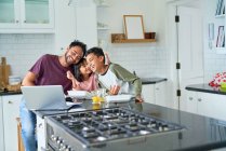 Verspielter Vater und Kinder essen und benutzen Laptop in der Küche — Stockfoto