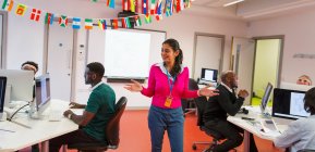 Instrutor universitário comunitário orientando estudantes adultos usando computadores em sala de aula — Fotografia de Stock