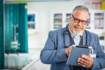 Чоловік лікар використовує цифровий планшет у клініці — стокове фото