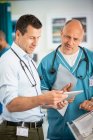 Чоловіки-лікарі консультуються, використовуючи цифровий планшет у лікарні — стокове фото