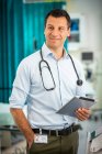 Портрет уверенный мужчина врач с помощью цифрового планшета в больнице — стоковое фото