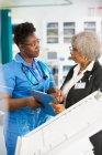 Ärztin und Krankenschwester mit Klemmbrett sprechen im Krankenhaus — Stockfoto