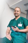 Ritratto fiducioso chirurgo maschio utilizzando smart phone — Foto stock