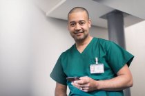 Уверенный в себе портрет, улыбающийся хирург с помощью смартфона — стоковое фото