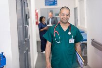 Portrait confident male surgeon walking in hospital corridor — Stock Photo