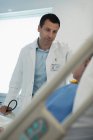 Догляд за чоловіком-лікар робить раунди, розмовляє з пацієнтом у лікарняній кімнаті — стокове фото