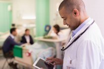 Médico masculino usando comprimido digital, fazendo rondas na enfermaria do hospital — Fotografia de Stock