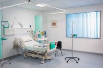 Cama de hospital, gotejamento IV e equipamentos médicos em quarto de hospital vago — Fotografia de Stock