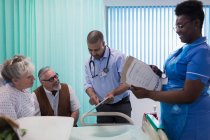 Arzt und Krankenschwester mit digitalem Tablet und medizinischem Diagramm im Gespräch mit einem älteren Ehepaar im Krankenhauszimmer — Stockfoto