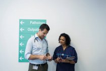 Врачи со смартфонами разговаривают в коридоре больницы — стоковое фото