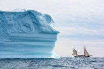 Barco navegando más allá del iceberg en el Océano Atlántico Groenlandia - foto de stock