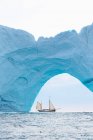 Ship sailing behind iceberg arch on Atlantic Ocean Greenland — Stock Photo