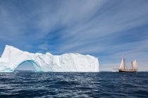 Barco navegando hacia el soleado majestuoso iceberg con arco Groenlandia - foto de stock