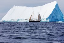 Nave che naviga oltre maestoso iceberg sulla soleggiata Groenlandia dell'Oceano Atlantico — Foto stock