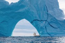 Sailboat under majestic iceberg arch Atlantic Ocean Greenland — Stock Photo