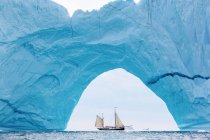 Ship sailing behind majestic iceberg arch Atlantic Ocean Greenland — Stock Photo