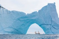 Ship sailing behind majestic iceberg formation on Atlantic Ocean Greenland — Stock Photo