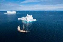 Корабель пливе повз величні айсберги в сонячному блакитному Атлантичному океані Гренландія — стокове фото