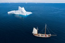 Schiff segelt am majestätischen Eisberg vorbei auf dem sonnigen blauen Atlantik Grönland — Stockfoto