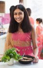Portrait smiling Indian girl in sari eating in kitchen — Stock Photo