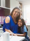 Portrait happy mother and daughter hugging in kitchen — Stock Photo