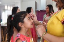 Индийская мать накладывает шнур на лоб улыбающейся дочери — стоковое фото