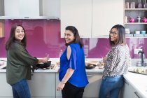 Portrait happy Indian sisters cooking food in kitchen — Stock Photo